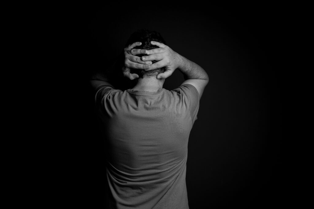 Black and white portrait of a man with hands on head, conveying stress and frustration.